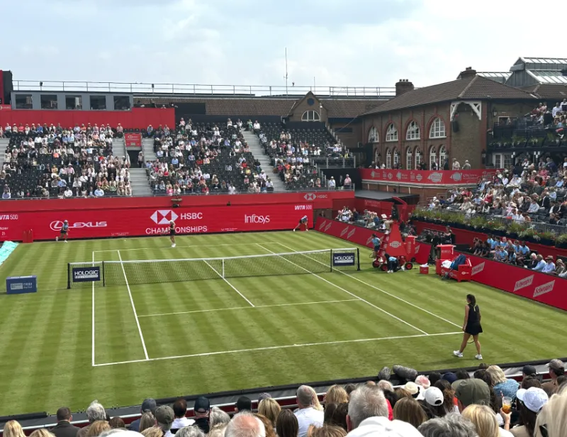 Spectators fill the stands of a professional grass-court tennis stadium 
