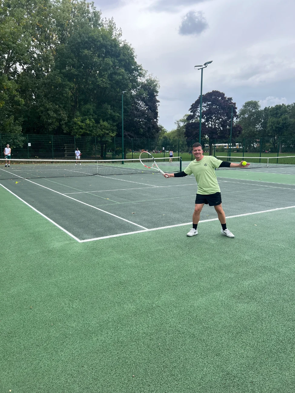 Tennis player smiles while showing off a green T-shirt.