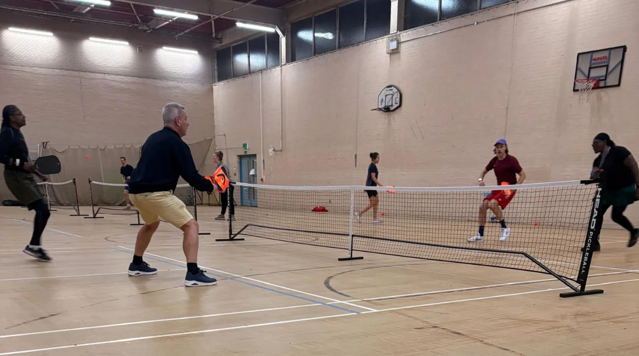 Four people playing indoor pickleball game.