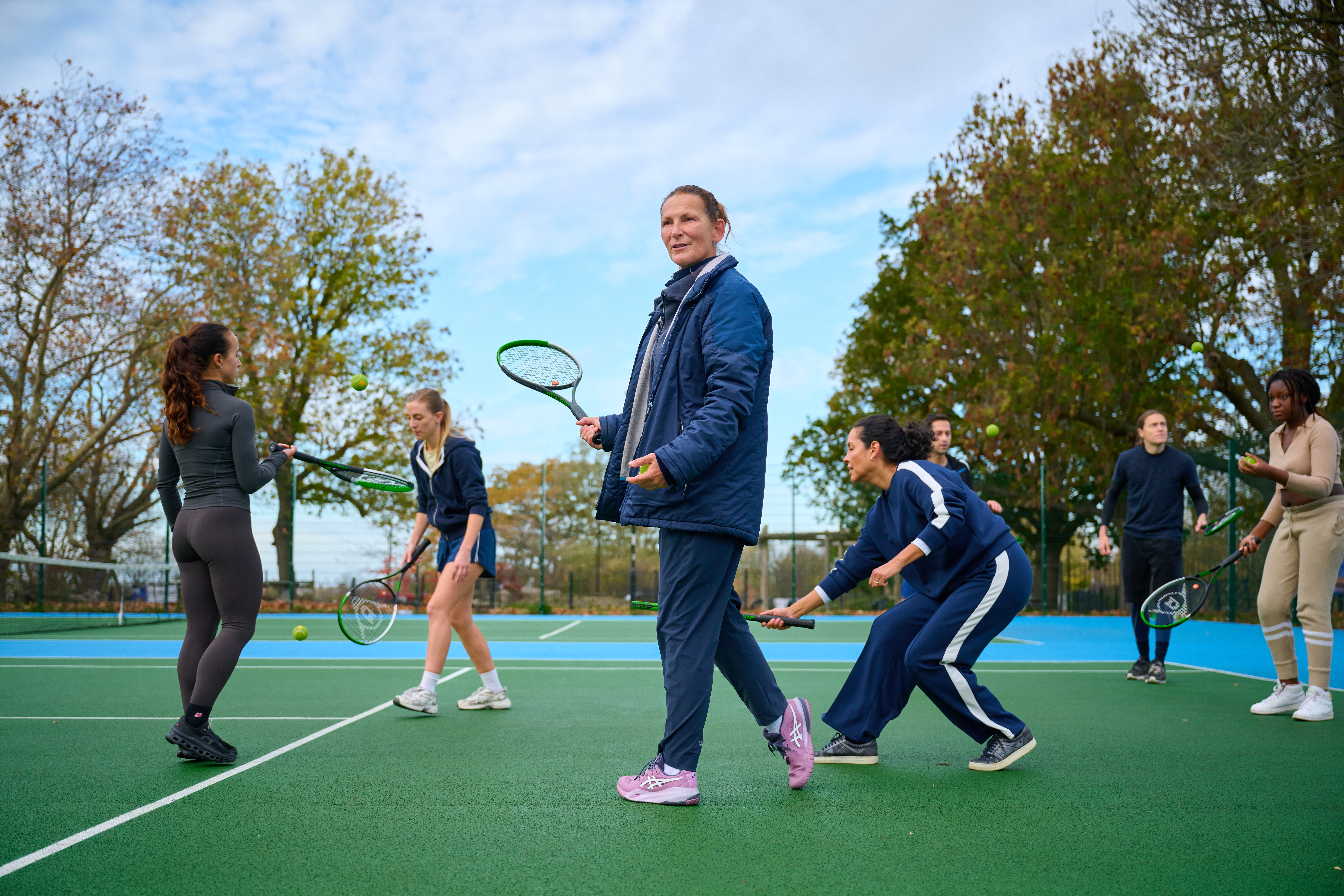 A female coach leads a women's tennis class