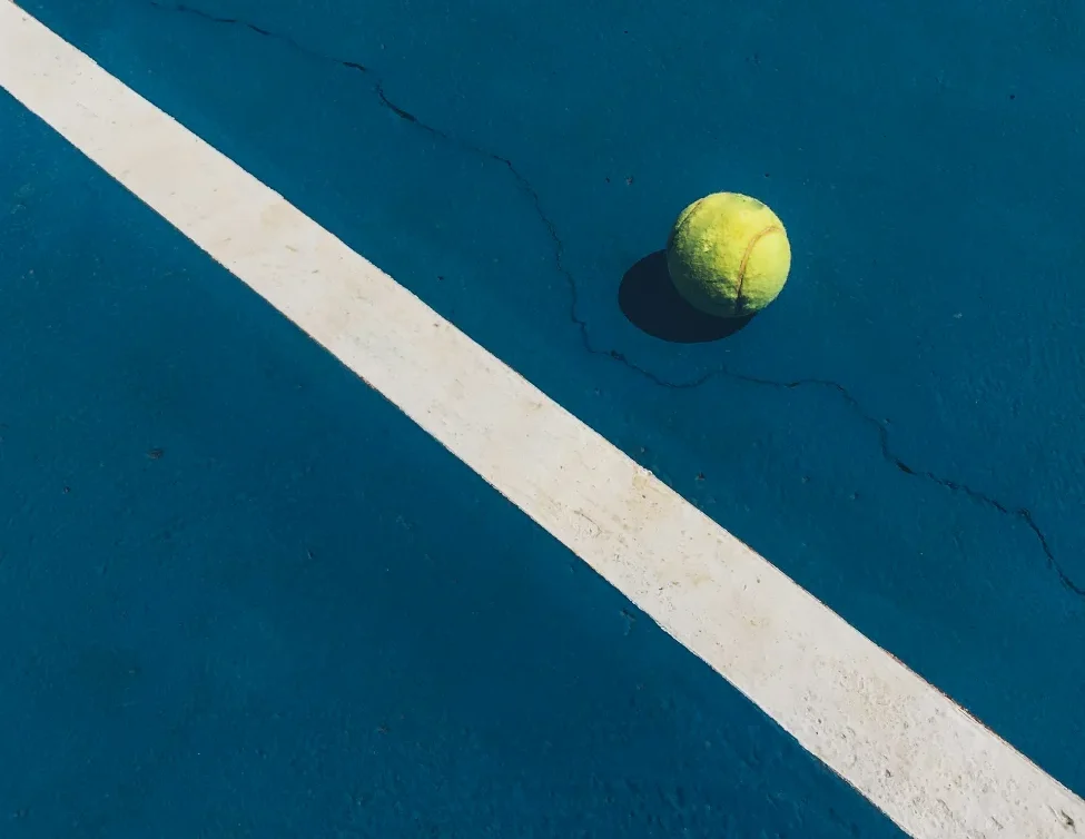 Tennis ball on blue court near line.