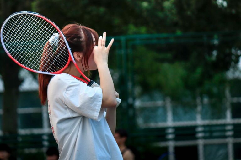 A girl playing tennis holds a hand to her face